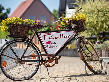 Ein altes Fahrrad, aufbereitet zu einem herzlichen "Willkommens-Schild" für Radler