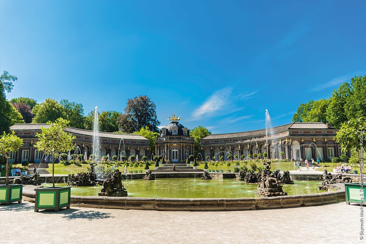 Ein schlossähnliches Gebäude mit Wasserspielen davor.