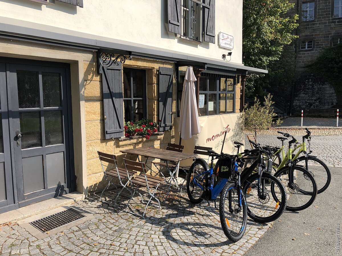 Ein Gasthaus mit Gelegenheiten, draußen zu sitzen, davor einige Fahrräder
