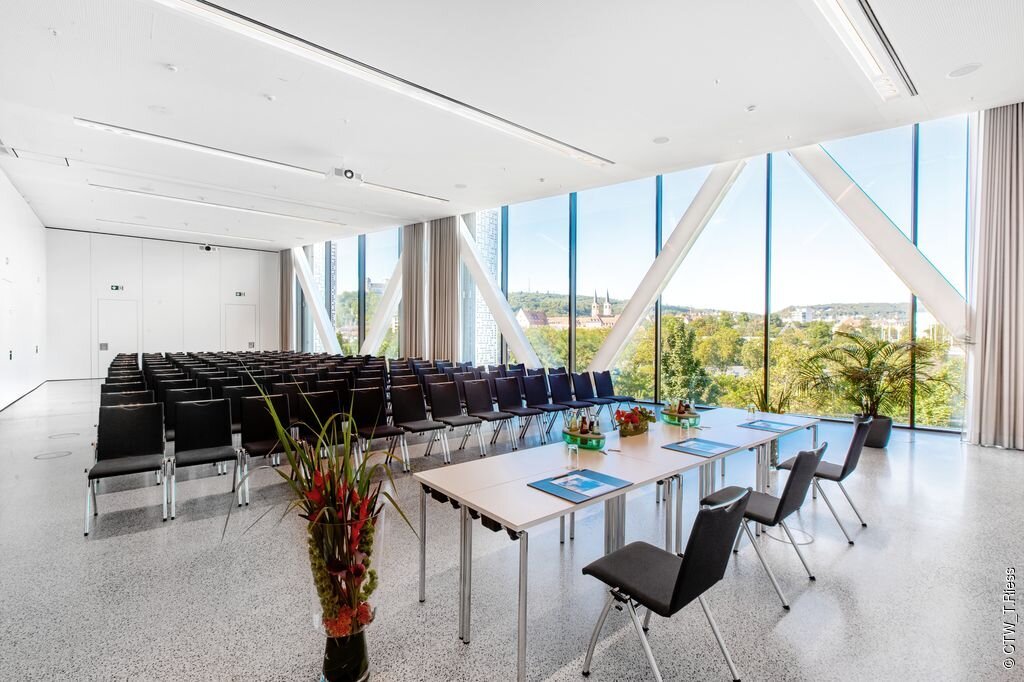 Tagungsraum im Congress Centrum Würzburg (Würzburg, Fränkisches Weinland) Konferenzraum mit Stuhlreihen, Tischen mit Unterlagen und großen Fenstern mit Stadtblick.