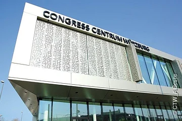 Fassade des Congress Centrums Würzburg mit großem Schriftzug und Glasfront bei klarem Himmel.